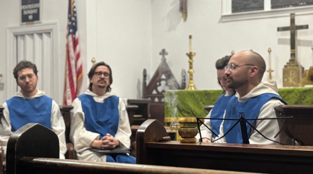 A reader at the lectern during Evensong while members of the Society in blue scapulars sit in the choir.