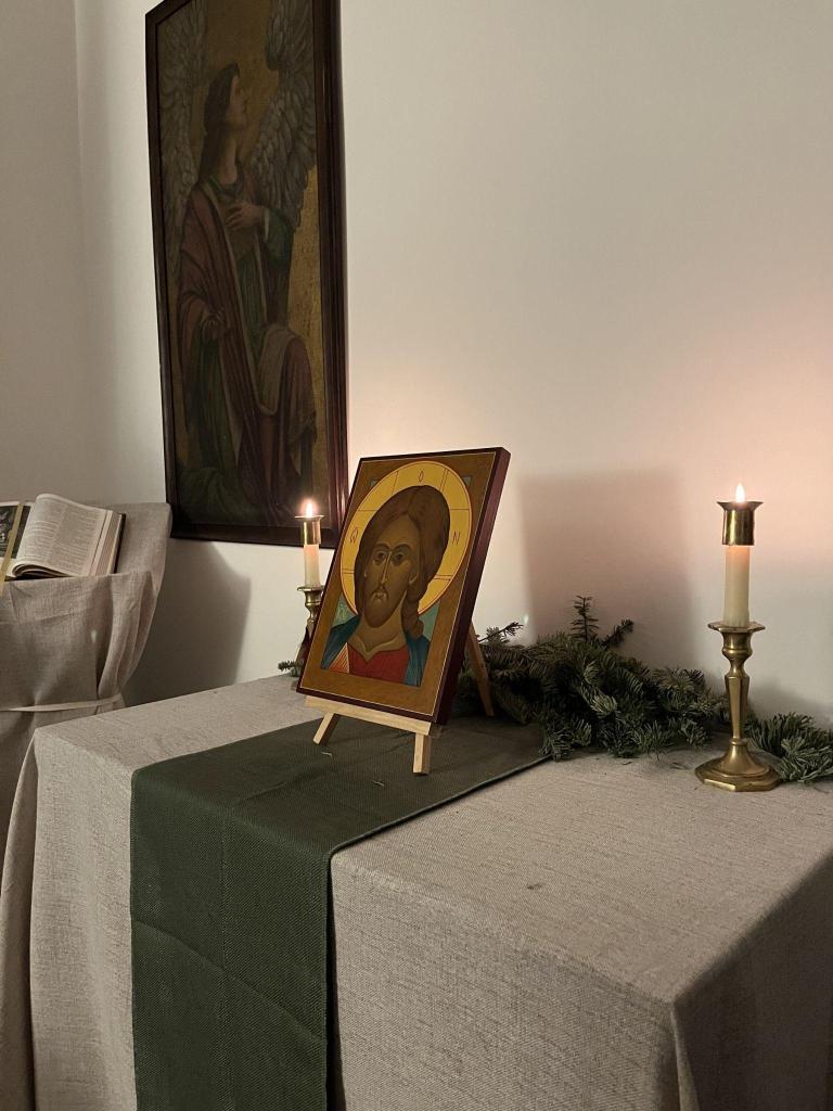 An icon of Christ between two lit candles on a linen-covered altar in the oratory of Saint Lawrence at Atonement House.